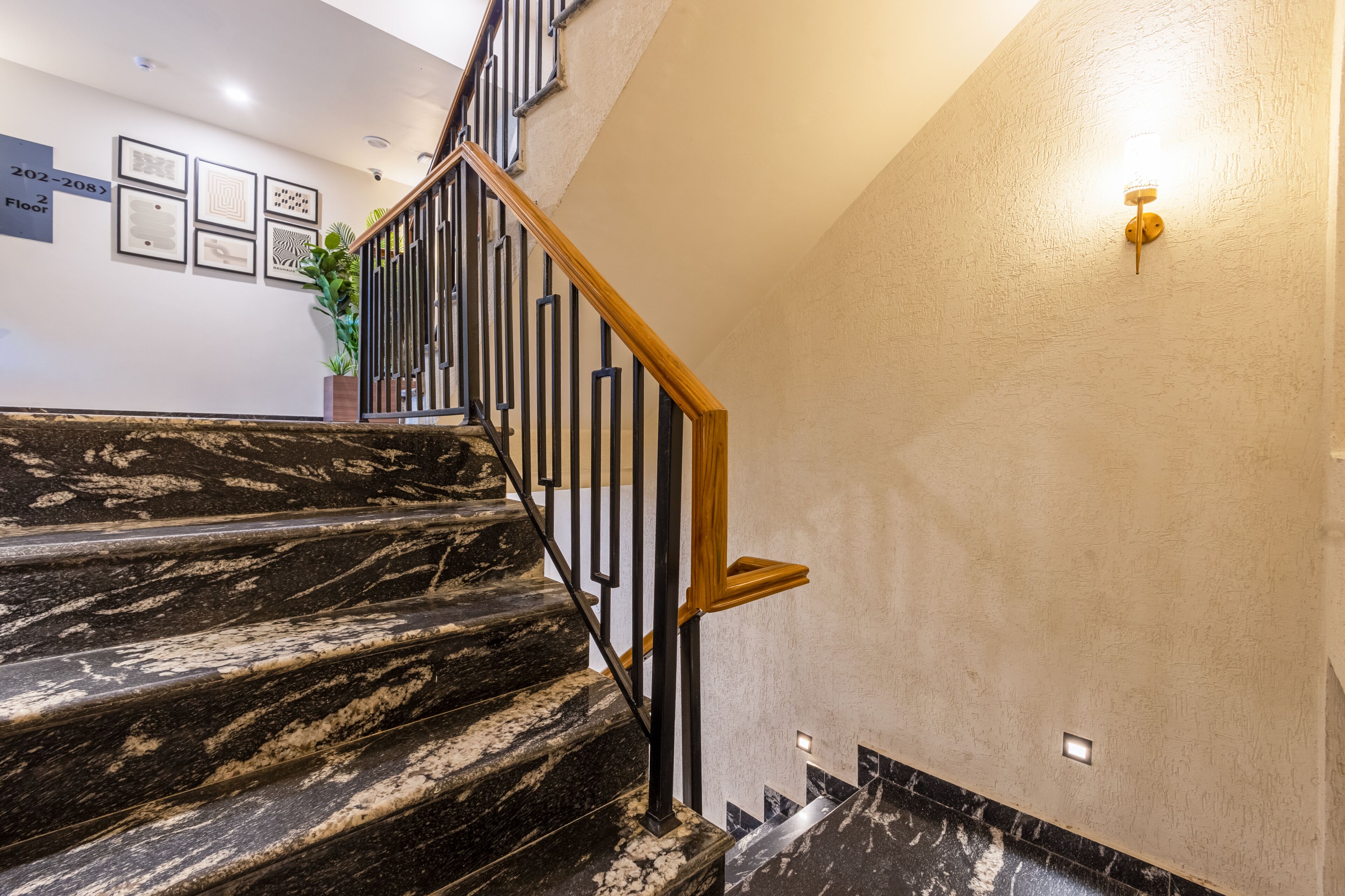 Un escalier en marbre, doté de rampes noires et d’une main courante en bois, menant à l’étage supérieur.