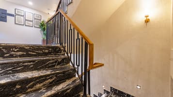 Un escalier en marbre, doté de rampes noires et d’une main courante en bois, menant à l’étage supérieur.