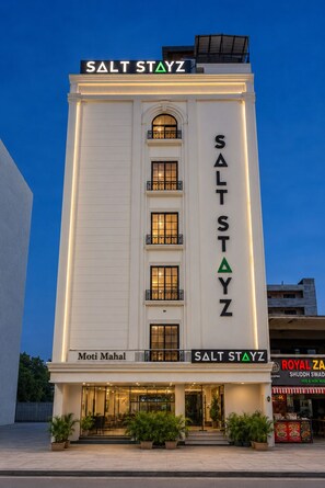 Un hotel anomenat 'Salt Stayz' amb una façana moderna, diverses finestres i un rètol de 'Moti Mahal' a l'entrada.