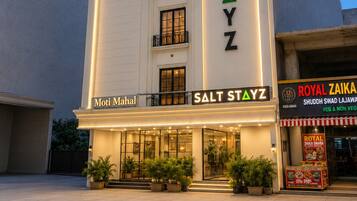 A hotel named 'Salt Stayz' with a modern facade, multiple balconies, and a sign for 'Royal Zaika' restaurant.