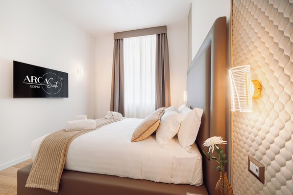 Una habitación de hotel con una cama, un televisor montado en la pared, una ventana con cortinas y una pared con textura.