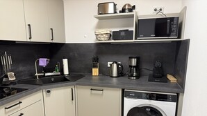 Eine kompakte Küche mit Geschirrspüler, Mikrowelle, Kaffeemaschine und Spüle mit modernen Küchenutensilien.