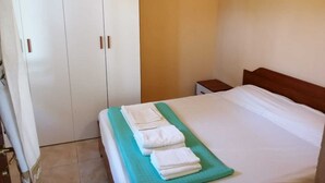 Hotellihuone, jossa on sänky, yöpöytä ja vaatekaappi.