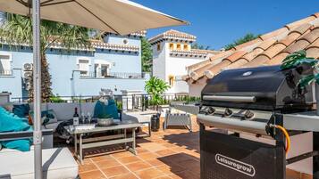 Eine Terrasse im Freien mit Grill, Sitzgelegenheit und Blick auf Gebäude.