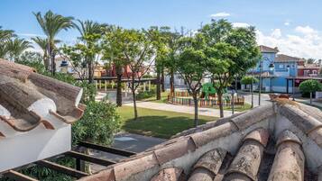 Zona residencial con un parque infantil, palmeras y edificios tradicionales.