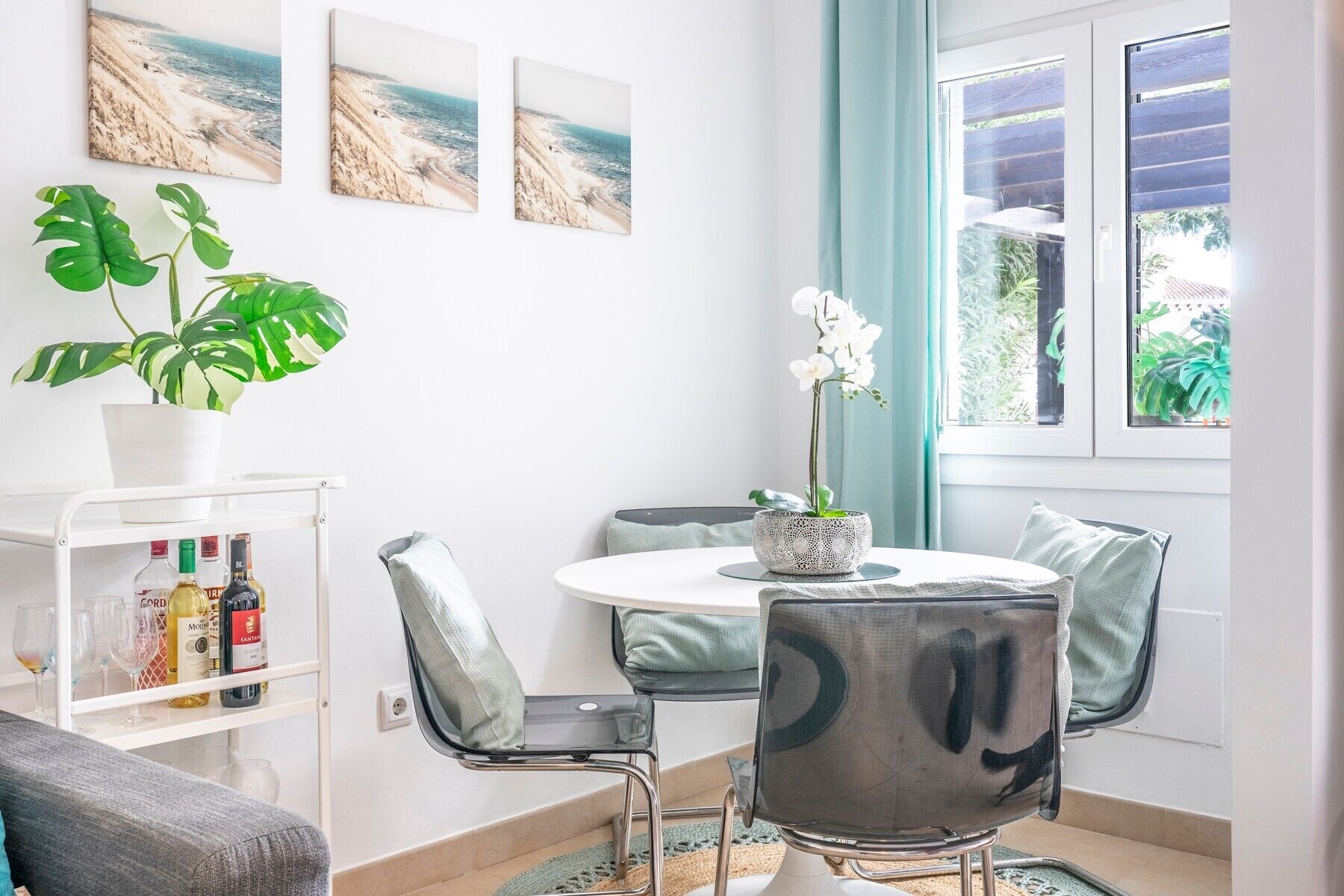 A modern dining area with a round table, chairs, a potted plant, and a view of the outdoors.