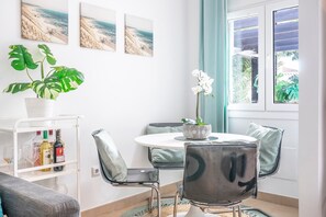 Un comedor moderno con una mesa redonda, sillas, una planta en maceta y vistas al exterior.