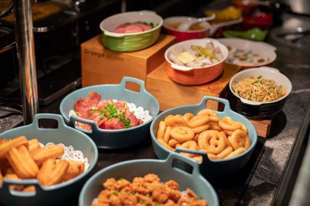 Un buffet proposant une variété de plats, notamment de la viande, des plats frits et des nouilles.