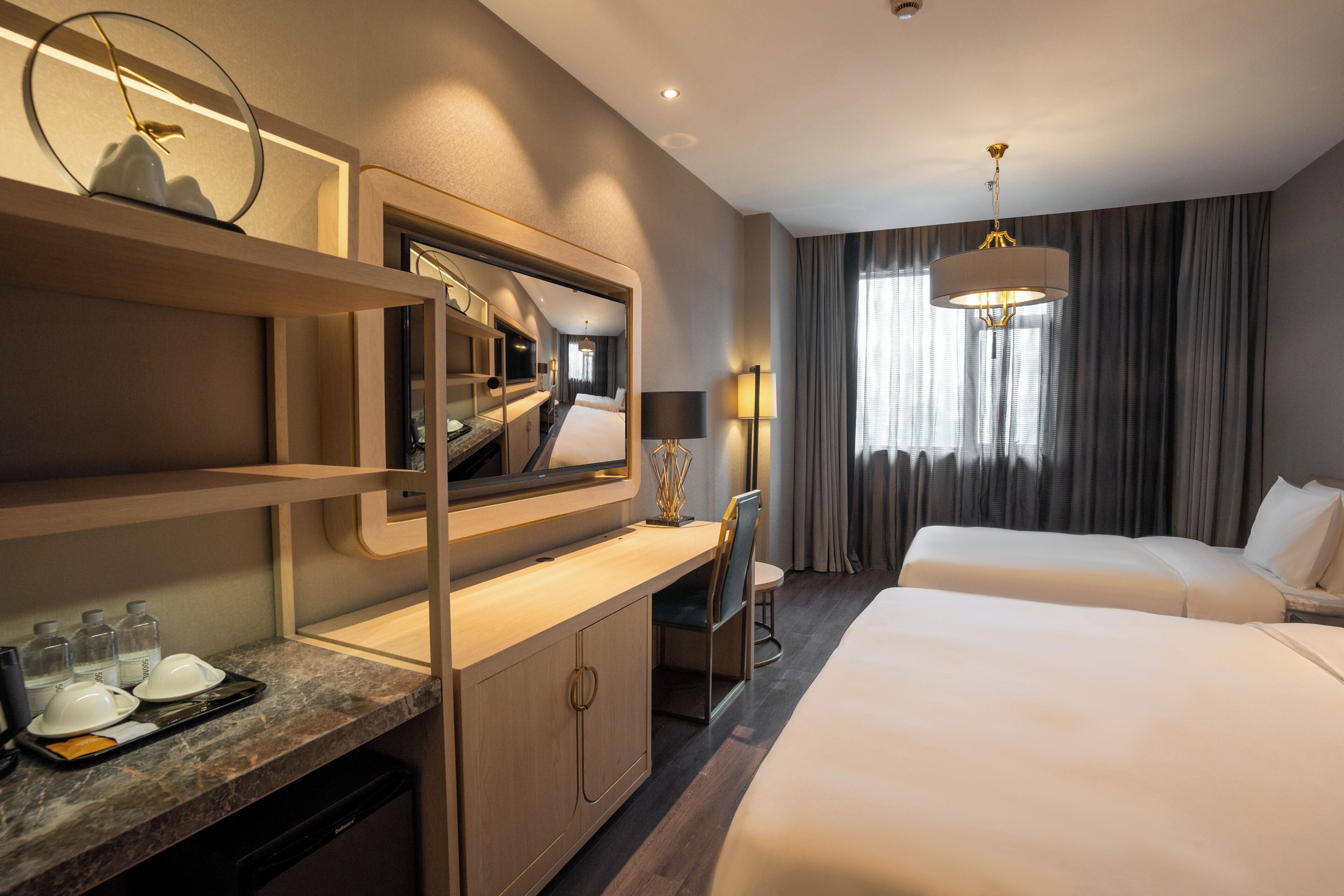 A hotel room with a bed, desk, chair, and a large mirror.