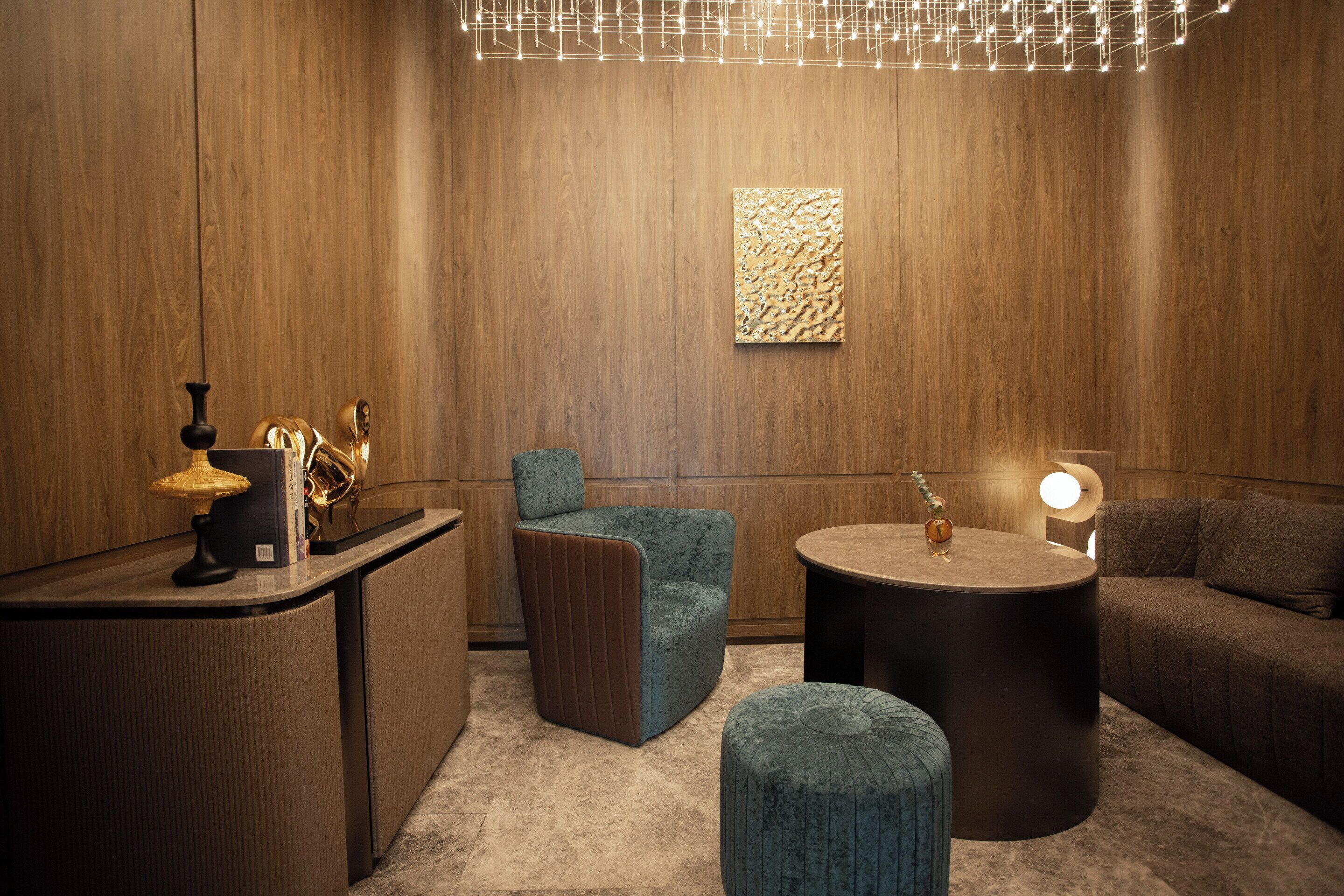 Ein modernes Interieur mit einer Holzwand, einem runden Tisch, einer Couch, einem kleinen Hocker und einer Lampe.