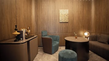 Ein modernes Interieur mit einer Holzwand, einem runden Tisch, einer Couch, einem kleinen Hocker und einer Lampe.