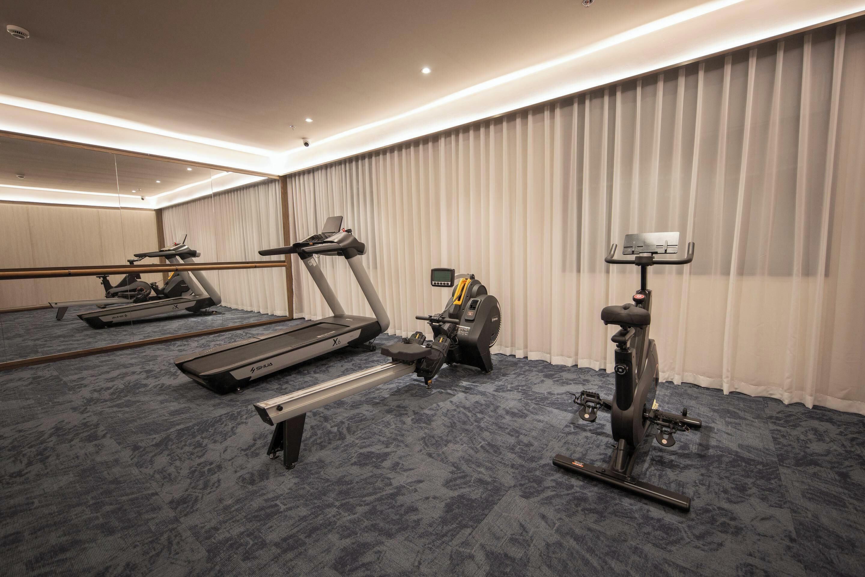 A hotel fitness room with a treadmill, elliptical, and stationary bike.