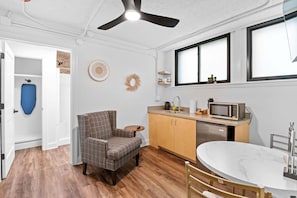 Una cocina compacta con microondas, lavabo y mesa de comedor.