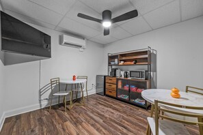 A compact kitchen with a dining area, a ceiling fan, an air conditioning unit, and a microwave. - Sabel #002 | Asheville Queen Suite w/ Kitchenette Near Downtown & Biltmore (Asheville)