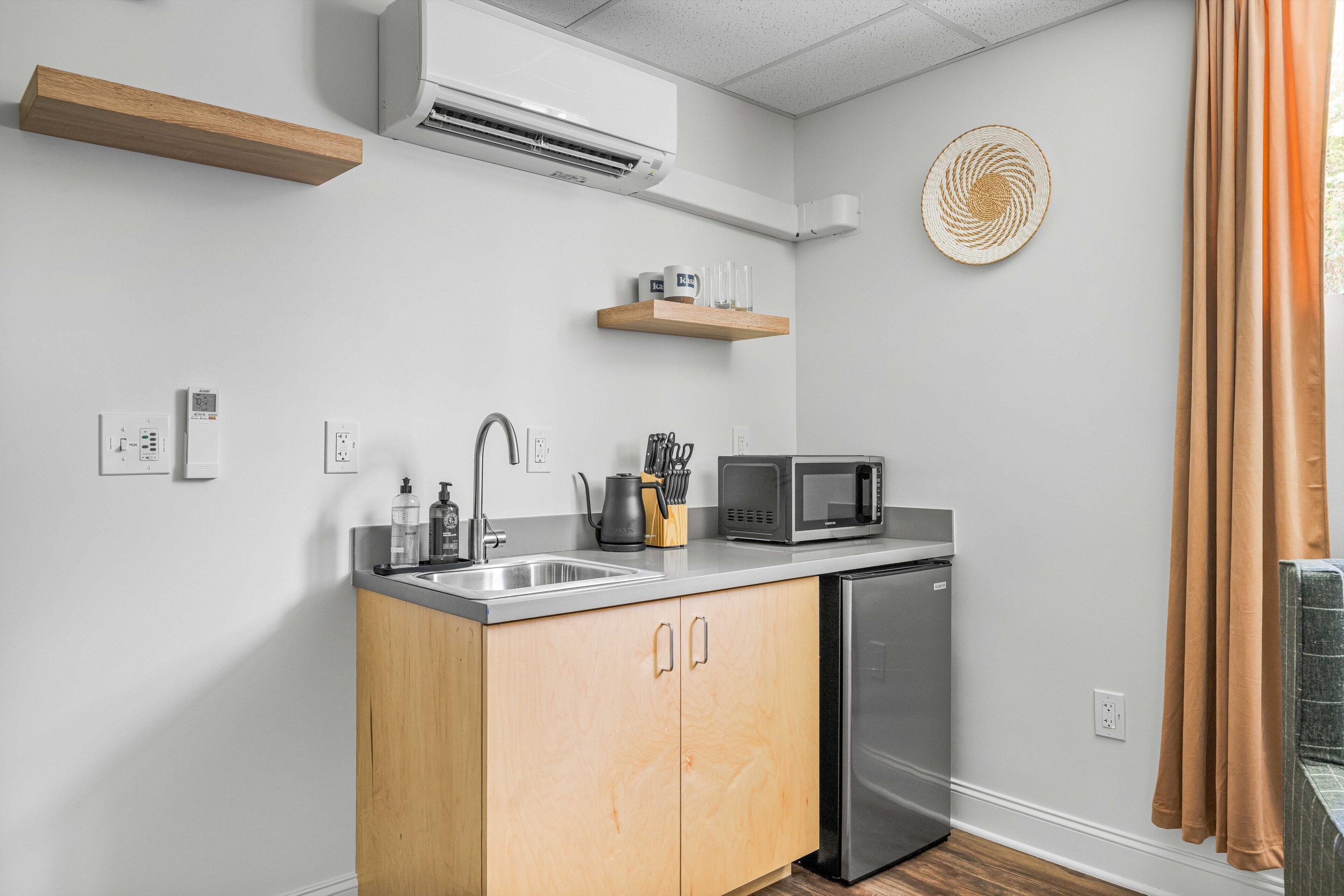 A compact kitchen with a dishwasher, microwave, and a wooden cabinet.