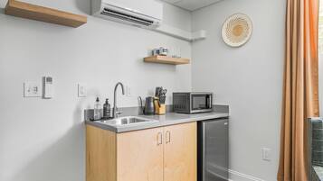 A compact kitchen with a dishwasher, microwave, and a wooden cabinet.