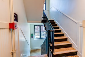 A staircase with wooden steps and black railings, leading to a landing with a window.