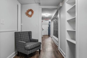 A hallway with a checkered armchair, a wreath on the wall, and a staircase with a patterned wall. - Sabel #004 | Downtown Asheville twin suite with bath, Wi-Fi, AC, and parking. (Asheville)
