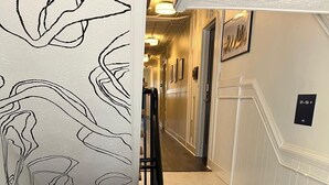 Eine Treppe mit Handlauf, Teppichstufen und einer Wand mit abstrakter Linienkunst.