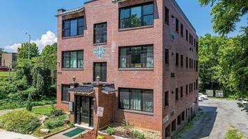 A multi-story brick building with a cross-shaped sign, a gated entrance, and a parking area.