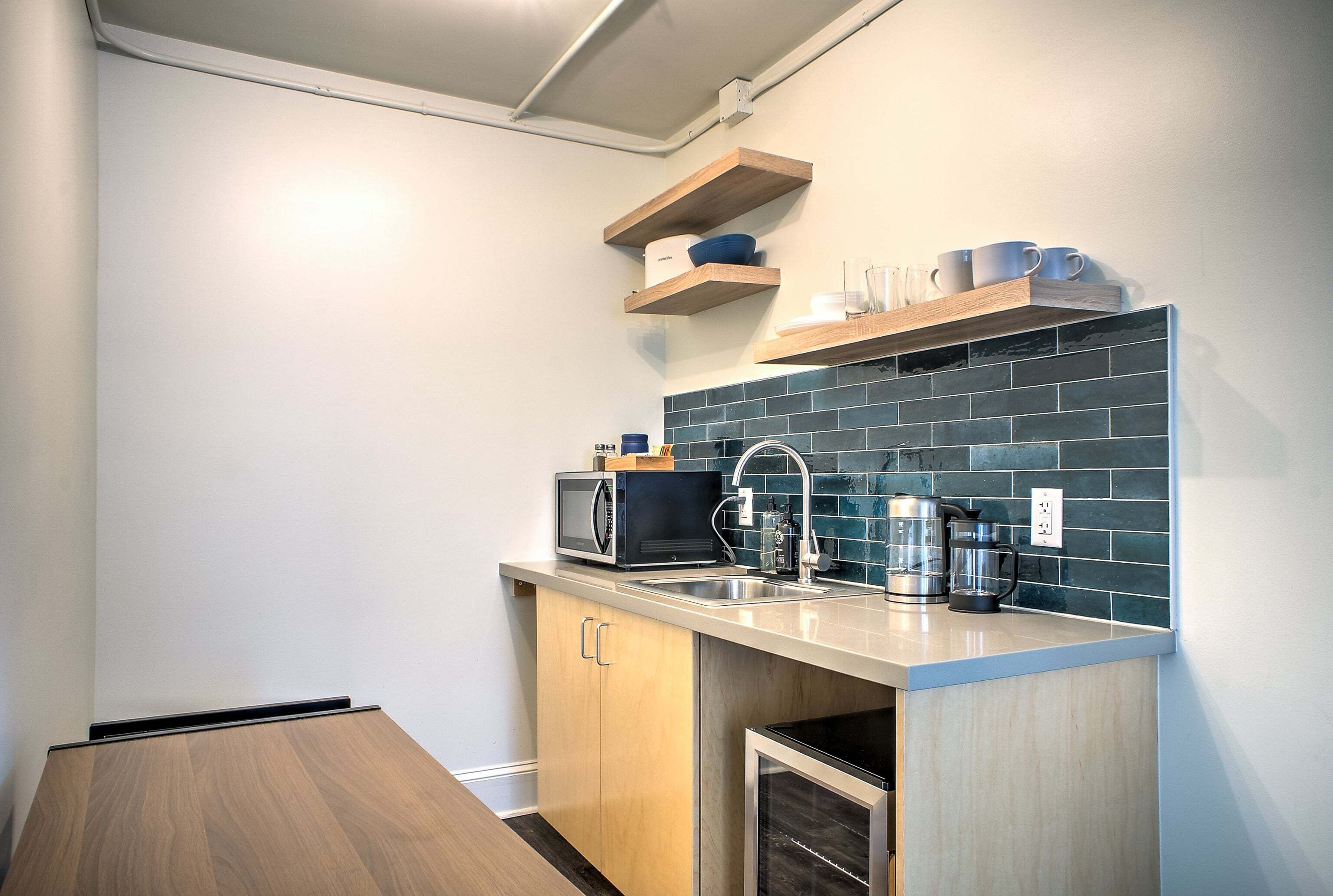 A compact kitchen with a microwave, coffee maker, and a sink.