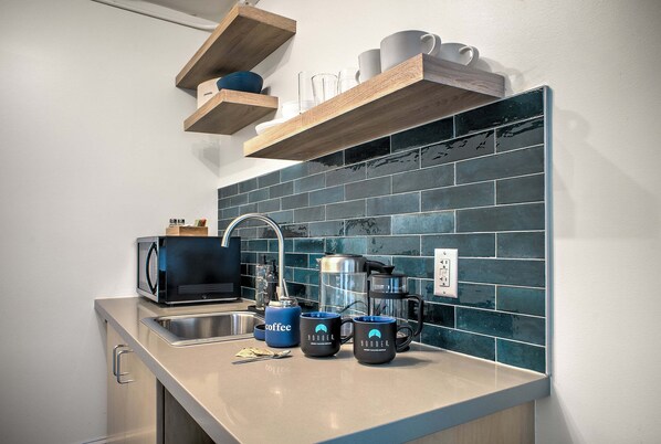A modern kitchen with a stainless steel sink, a coffee maker, and a microwave.