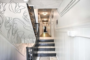 A staircase with a black railing and a wall with a black and white abstract design. - Sabel #103 Downtown Asheville king suite with Wi-Fi, parking, and kitchenette (Asheville)