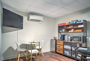 A compact kitchenette with a microwave, a small refrigerator, and a shelf with various items. - Sabel #104 | Downtown Asheville king suite with Wi-Fi, parking, and mini fridge. (Asheville)