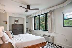 A bedroom with a bed, a dresser, a ceiling fan, a window with curtains, and a radiator. - Sabel #104 | Downtown Asheville king suite with Wi-Fi, parking, and mini fridge. (Asheville)