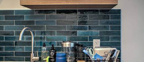 A kitchen with a stainless steel sink, a coffee maker, and a variety of kitchen utensils.