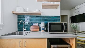 Coffee/tea maker, microwave, cookware/dishes/utensils, dining tables