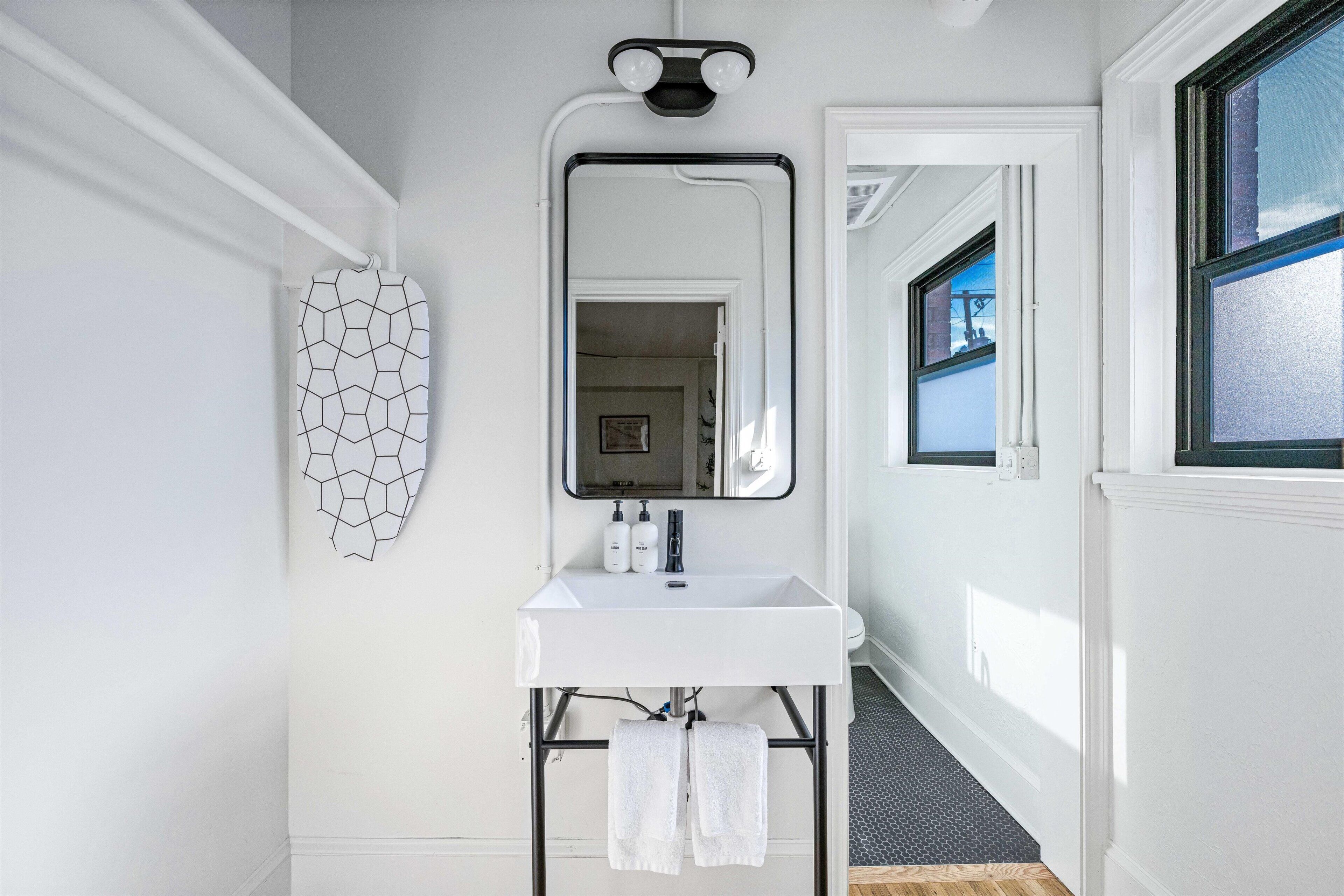 A bathroom with a white sink, a mirror, and a hexagonal wall decoration.