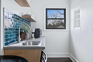 Eine kleine Küche mit Spüle, einem Fenster und schöner Aussicht sowie einer Spritzschutzwand.