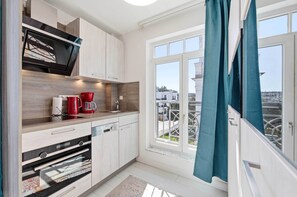 Eine moderne Küche mit integrierten Geräten, einem Fenster mit Vorhängen und Blick auf die Stadt.