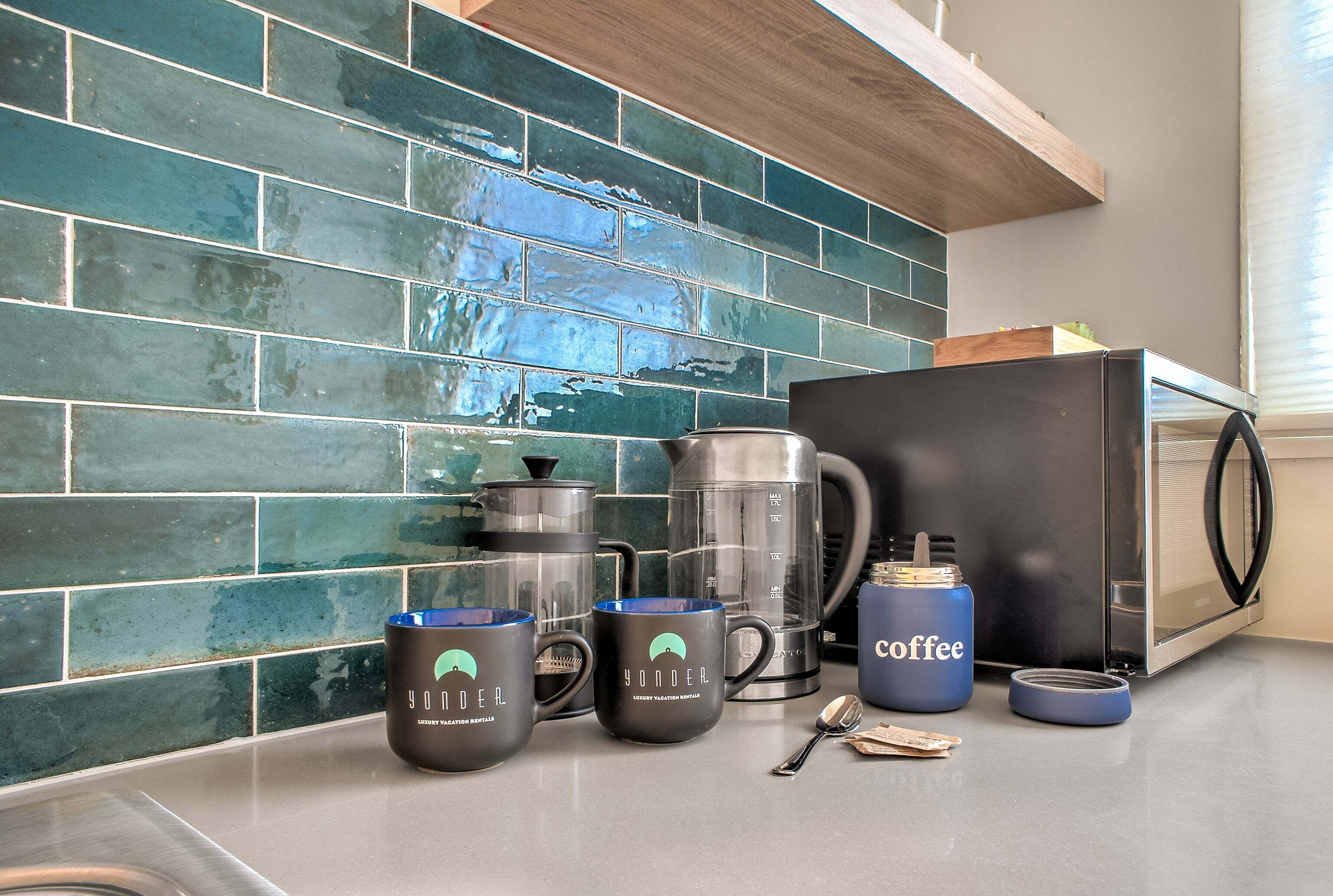 A kitchen counter with a coffee maker, two mugs, a thermos, and a toaster.