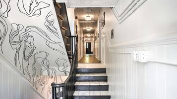 Un escalier avec une rampe noire et un mur orné d’un motif abstrait en noir et blanc.