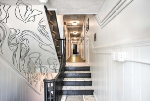 A staircase with a black railing and a wall with a black and white abstract design. - Sabel #101 | Downtown Asheville studio with mountain views, Wi-Fi, and parking. (Asheville)
