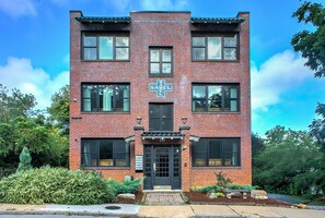 A two-story brick building with a symmetrical facade, large windows, and a central entrance. - Sabel #101 | Downtown Asheville studio with mountain views, Wi-Fi, and parking. (Asheville)