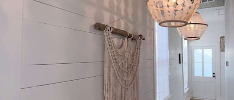 A hallway with wooden paneling, macramé wall hangings, and pendant lighting.