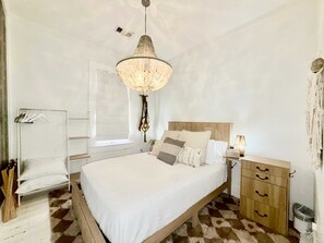 Ein Schlafzimmer mit Bett, Nachttisch, Lampe und einer Pendelleuchte.