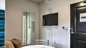 Et hotelværelse med et marmorbadeværelse, et fjernsyn ophængt på væggen og en dør med en evakueringsplan.