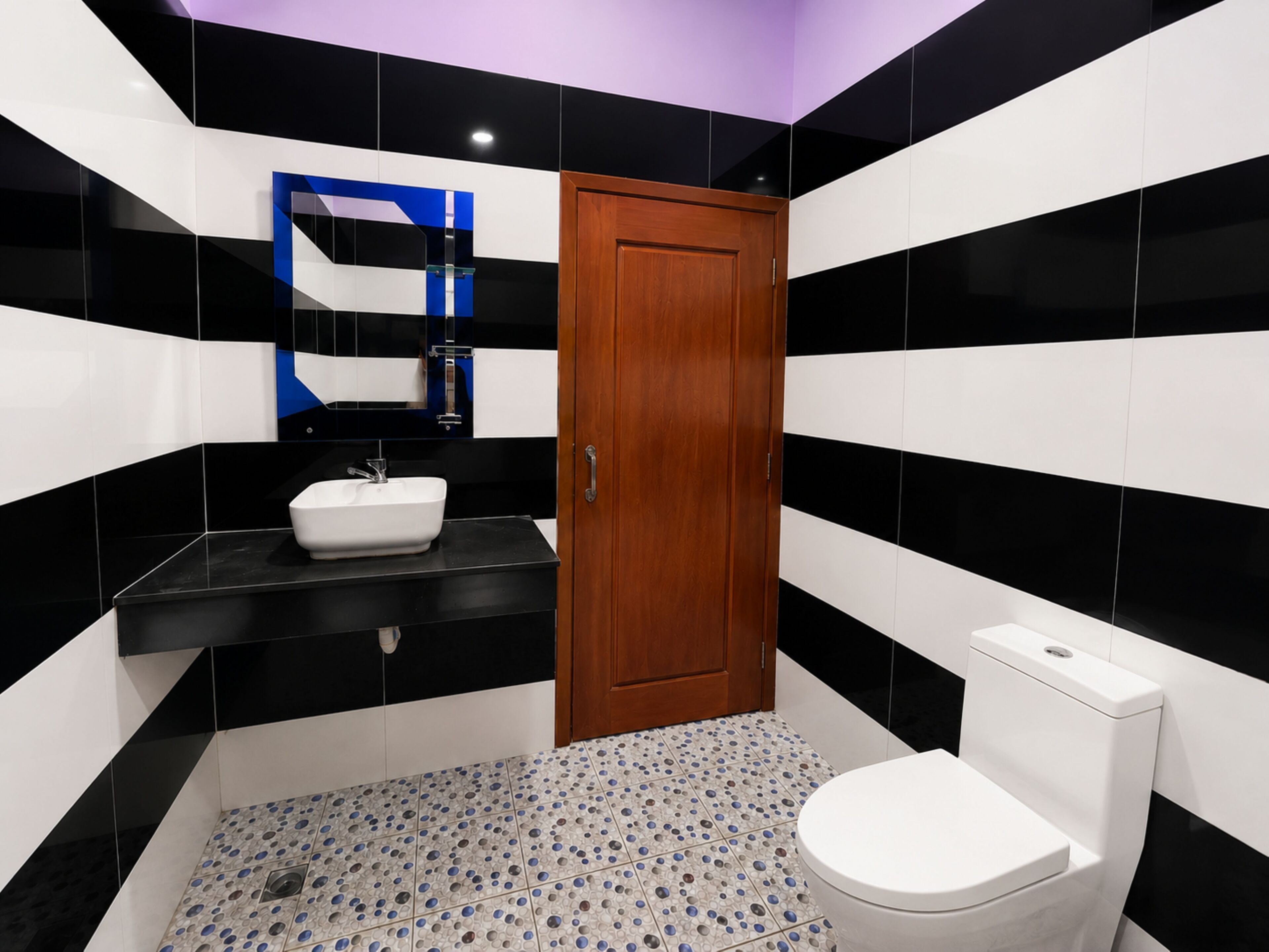 Baño con lavamanos blanco, puerta de madera y retrete.