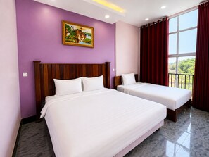 A hotel room with two beds, a wooden headboard, a purple wall, a painting, and a window with curtains. - Cloudy Hill Hostel & Villa (Kampot)