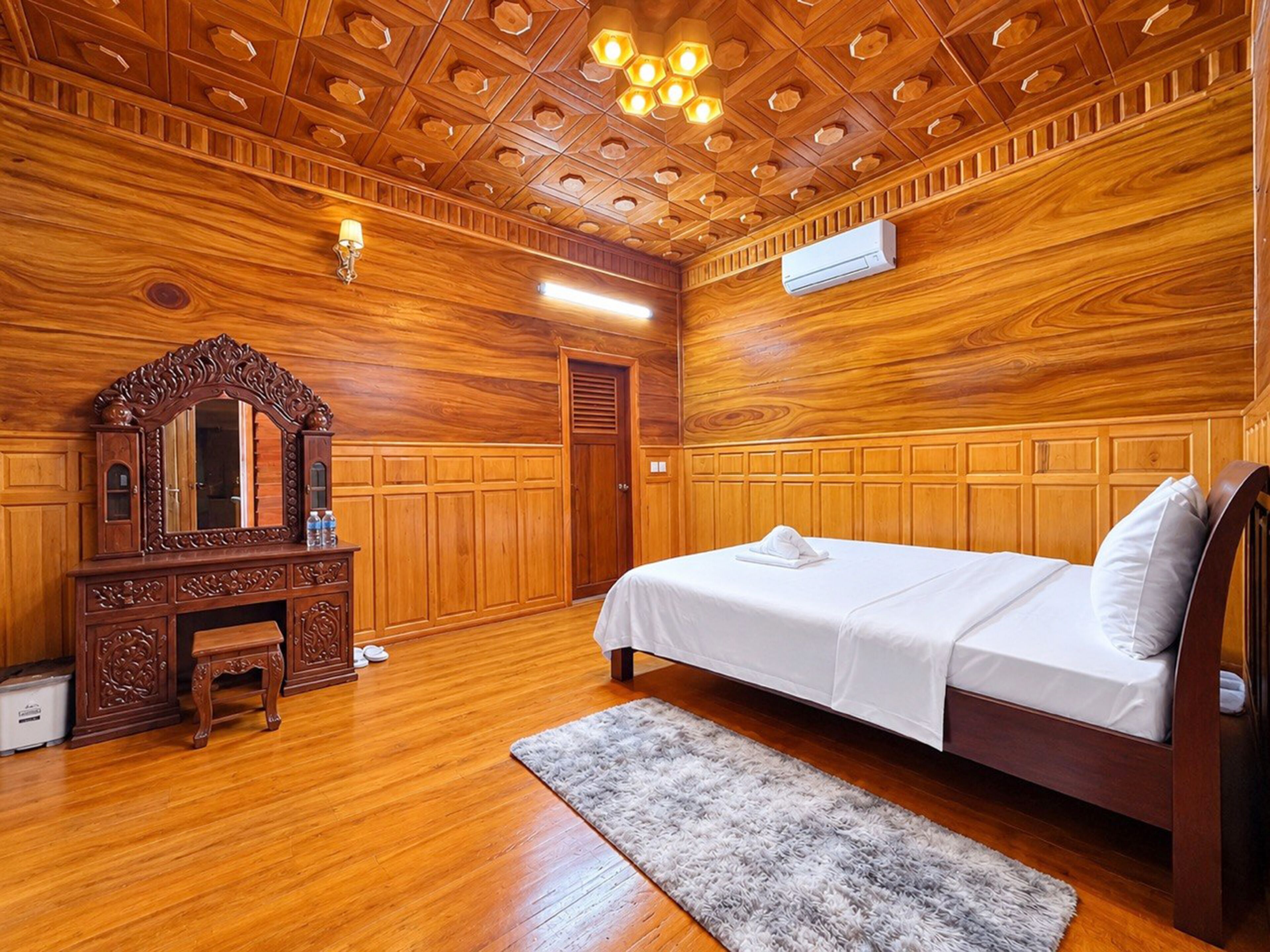 A wooden-paneled room with a bed, a dresser, and a mirror.