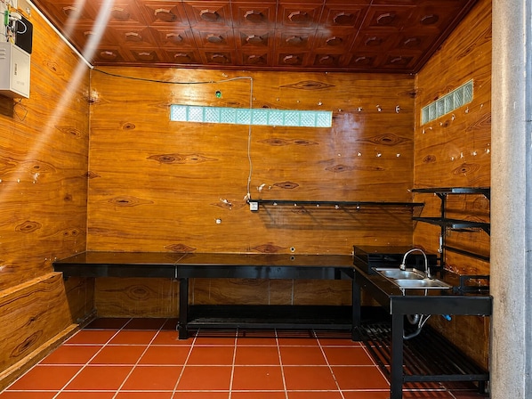 A compact kitchen with wooden walls, a tiled floor, and a built-in sink.