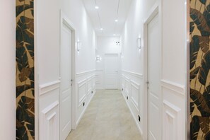 A hallway with white walls, a patterned wall on the left, and a door at the end. - Alivella (Naples)