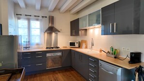 A modern kitchen with grey cabinets, a stainless steel range hood, a microwave, and a dishwasher. - Ferienhaus 'Domaine de Bellac - 32 Personen' mit privatem Pool, Terrasse und WLAN (Roussines)