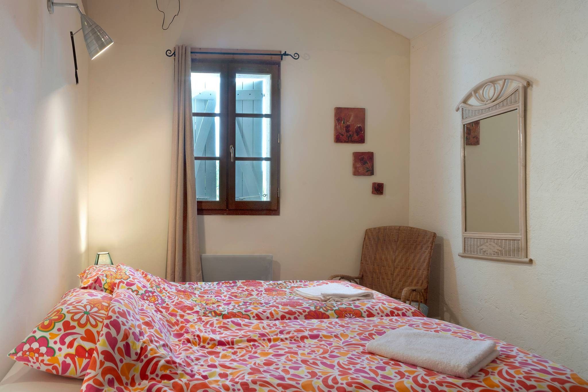 Quarto com cama, cadeira, janela e espelho.