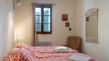 Quarto com cama, cadeira, janela e espelho.