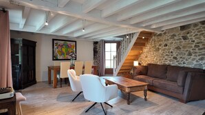 A spacious room with a dining area, a sofa, and a staircase leading to an upper level. - Ferienhaus 'Domaine de Bellac - 32 Personen' mit privatem Pool, Terrasse und WLAN (Roussines)